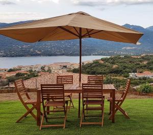 普罗普里亚诺Appartement neuf 3 chambres vue mer Propriano的一张带椅子的木桌和一把伞