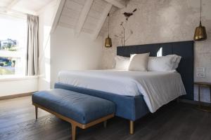 莱科LUXURY SUITES ROCOPOM - Lake Front的一间卧室设有一张大床和一张蓝色长凳