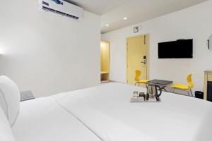 博帕尔FabHotel Oasis Yellow Courtyard的一间设有床铺和墙上电视的客房