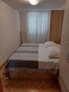 拉布Apartments Mlacovic的一个小房间的一个床位,设有窗户