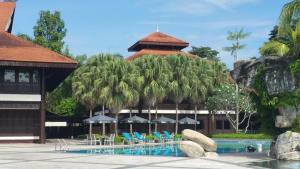 士姑来Garden View Pulai Springs Resort的一个带椅子和遮阳伞的游泳池的度假酒店
