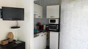 比亚里茨Belle Suite Apt的一间带白色橱柜和微波炉的厨房以及一台电视。
