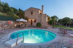 圣特里亚斯Cretan Exclusive Villas的石头房子前面的游泳池