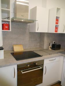 奥赛Spacieux F5 au parc arboré的厨房配有白色橱柜和炉灶烤箱。