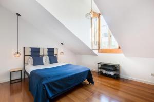 里斯本Stunning and Spacious Lofts just by Graça and Alfama的一间卧室配有一张带蓝色毯子的床和两个窗户。