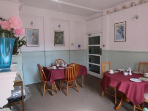 邓迪Athollbank Guest House的一间用餐室,配有两张带紫色桌布的桌子