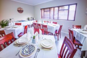 SandtonAtlantic Pearl Guest House Broadacres的用餐室配有白色的桌子和红色的椅子