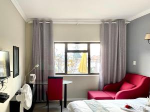 SandtonAtlantic Pearl Guest House Broadacres的一间设有床铺、红色椅子和窗户的房间