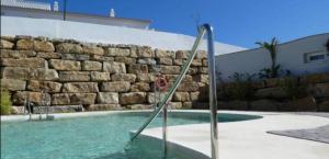 萨阿拉德洛斯阿图内斯Agradable casa adosada con piscina的游泳池内的水滑梯,带有石墙