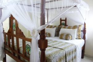 马林迪Tembo Court Apartments的卧室配有带白色窗帘的天蓬床