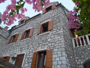 苏佩塔尔Vila Dora Supetar的一座石头建筑,设有窗户和粉红色的鲜花