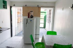 特雷西纳FLAT ACONCHEGANTE的厨房配有桌子、绿色椅子和冰箱