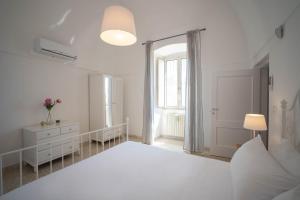 莫诺波利Porta Sugli Ulivi的白色的卧室设有一张大床和一个窗户