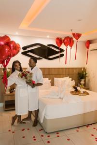 卡波布里奥帕拉迪索公司酒店的男人和女人站在床边,拿着气球