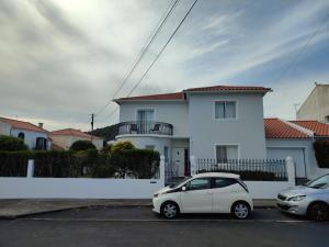 蓬塔德尔加达Casa da Isabelinha的两辆汽车停在白色房子前面