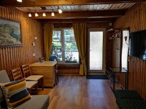 奈达Mini Kotedžas Vakaris的客厅设有木镶板、书桌和窗户。