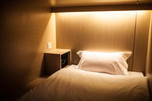 曼谷Cubic Bed Pratunam的一间卧室配有带枕头和床头柜的床
