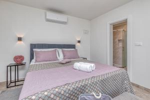 波雷奇Rooms Nilda的白色卧室配有一张带紫色床单的大床