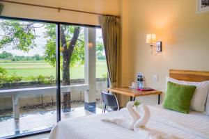 七岩Tontan Resort Cha-am的一间卧室配有一张床、一张书桌和一个窗户。