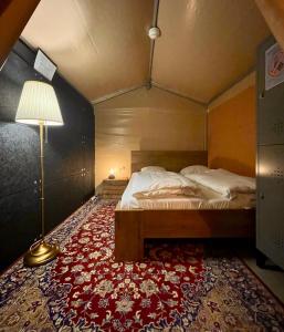 哥本哈根Urban Camper Hostel & Bar的卧室配有一张床和红色地毯上的灯