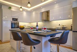 罗达Noufris House Roda Corfu的厨房配有带椅子和酒杯的岛屿