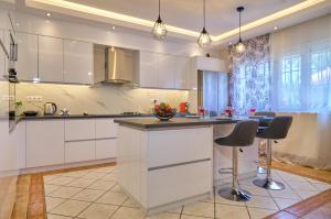 罗达Noufris House Roda Corfu的一间厨房,配有白色橱柜和一个带酒吧凳的岛屿