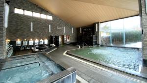 大崎市Tabinoyado Yakurai Rinsenkan的一座大型游泳池,位于一座带大窗户的建筑内