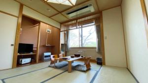 大崎市Tabinoyado Yakurai Rinsenkan的客房设有桌椅和窗户。