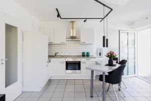 农嫩霍恩Ferienwohnung im Fischerhaus的厨房配有白色橱柜和桌椅