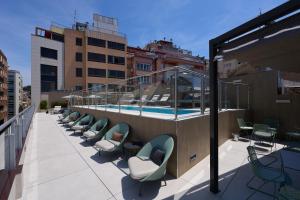 巴塞罗那加泰罗尼亚巴塞罗那505号酒店的一个带椅子的阳台和一个位于大楼内的游泳池