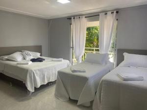 伊瓜苏Pousada Maria`s Inn - Conforto, acolhimento e qualidade em Foz do Iguaçu的带窗户的客房内的两张床