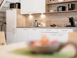 厄茨MYALPS Mühlhof的厨房配有白色橱柜和一碗食物