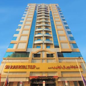 沙迦Sharjah Royal Tulip Hotel Apartments توليب رويال الشارقة的一座高大的建筑,上面标有酒店标志