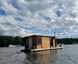 柏林Gemütliches Hausboot mit Kamin in Berlin的水体上码头上的一个小房子