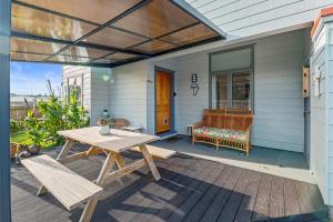 新普利茅斯Ekhaya - New Plymouth Holiday Home的庭院设有野餐桌和房子内的长凳
