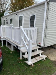 Lytchett MinsterNew 2 bed holiday home with decking in Rockley Park Dorset near the sea的白色移动房屋,设有楼梯和门廊