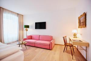 格蒙登Boutiquehotel Zum Goldenen Hirschen的客厅配有粉红色的沙发和桌子