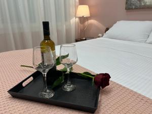 卡瓦拉Kavala Port Apartments的床上的托盘,上面放有两杯酒和一瓶葡萄酒