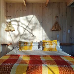 马拉卡韦罗Malalcahuello Eco Glamp的一间卧室配有一张带彩色毯子的床