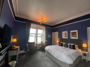 奥本Barriemore Oban的一间卧室设有蓝色的墙壁、一张床和电视。