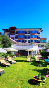 迈尔霍芬Alpenhotel Stefanie - direkt buchbar的一座楼前设有草坪椅和遮阳伞的酒店