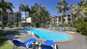 黄金海岸太古广场酒店式公寓 的一个带蓝色椅子的游泳池,棕榈树