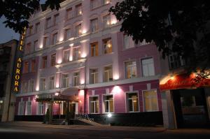 哈尔科夫极光精品酒店的粉红色的建筑,旁边灯