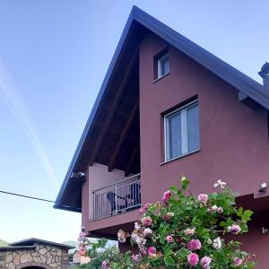 科尼茨Villa Pjene的一座粉红色的建筑,设有阳台,并种植了鲜花