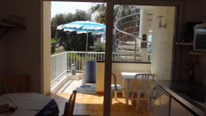 萨戈内Residence Funtanella的阳台的厨房配有桌子和雨伞