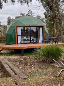 卢汉Don Aniceto Lodges & Glamping的绿色帐篷,配有桌子和长凳