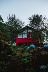 康塞高伊比蒂波卡Sítio das Hortênsias Chalés的前方有树木和鲜花的红色房子