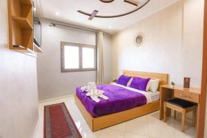 阿尤恩HOTEL BEAUPORT的一间卧室配有一张带紫色床单的床和窗户。
