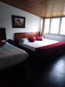波哥大Casa Hotel Victoria的一间卧室配有两张带红色枕头的床。