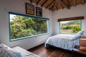 莱瓦镇Casa Mediterránea Villa de Leyva的一间卧室设有两张床和大窗户